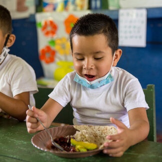 Un écolier savoure son repas fourni avec le soutien du programme d'alimentation scolaire du PAM.